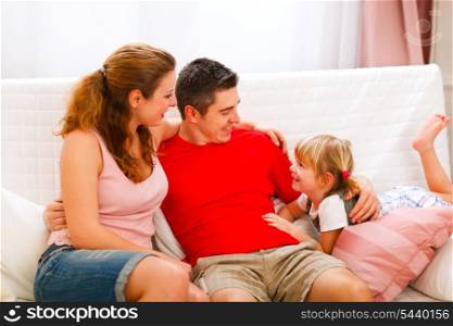 Mother father sitting on couch and talking with daughter