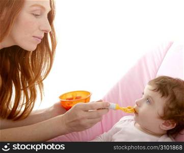 mother feeding baby yellow spoon white background