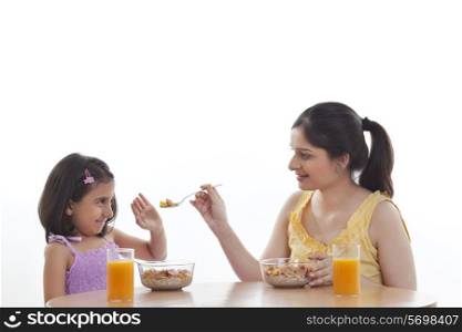 Mother feeding her daughter breakfast