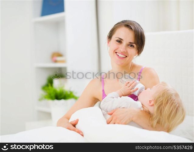 Mother feeding kid in bed