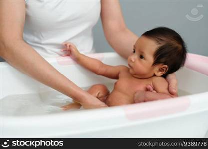 mother give a bath newborn baby in a bathtub