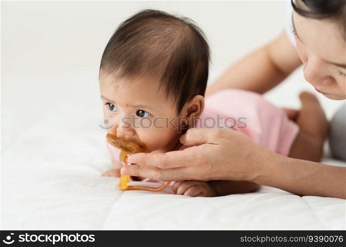 mother gives a pacifier to her infant baby girl on a bed 