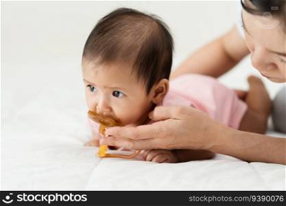 mother gives a pacifier to her infant baby girl on a bed 