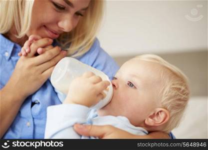 Mother Giving Baby Son Bottle Of Milk