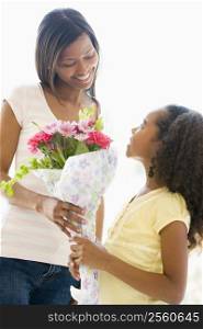 Mother giving daughter flowers and smiling