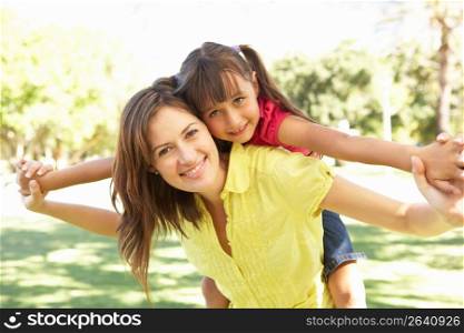 Mother Giving Daughter Ride On Back In Park
