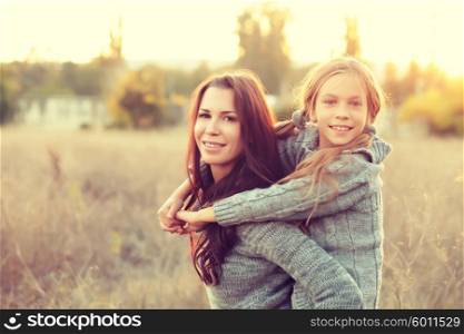 Mother giving her daughter a piggyback ride