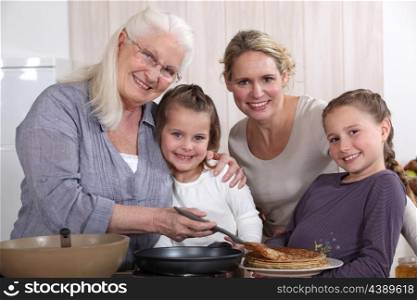 Mother, grandmother, and girls cooking pancakes