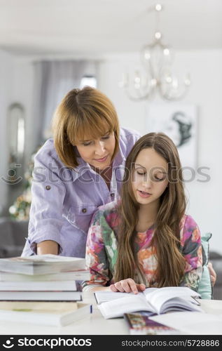 Mother guiding daughter in doing homework at table