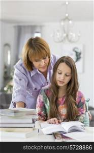 Mother guiding daughter in doing homework at table