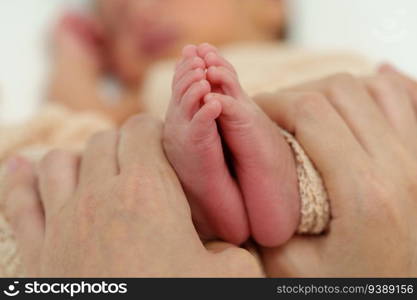 mother hand holding newborn baby feet on a bed