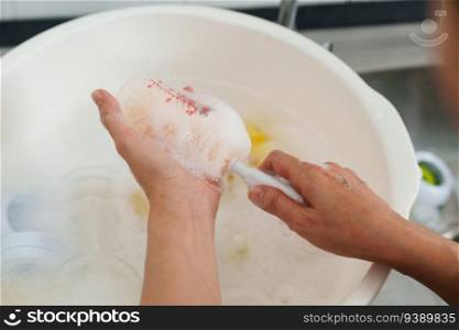 mother hand washing the baby plastic milk bottle
