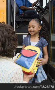 Mother Handing Daughter Backpack on School Bus