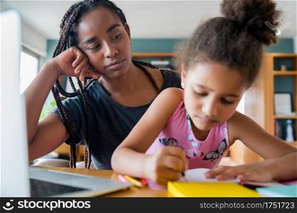 Mother helping and supporting her daughter with online school while staying at home. New normal lifestyle concept. Monoparental concept.