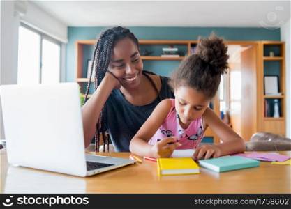 Mother helping and supporting her daughter with online school while staying at home. New normal lifestyle concept. Monoparental concept.