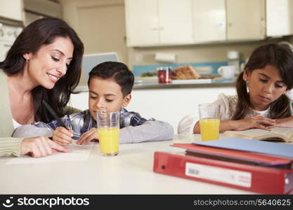 Mother Helping Children With Homework At Table