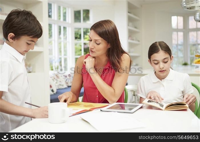 Mother Helping Children With Homework Using Digital Tablet