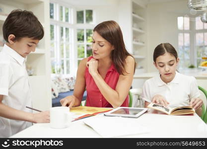 Mother Helping Children With Homework Using Digital Tablet