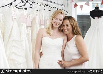 Mother Helping Daughter To Choose Dress In Bridal Store
