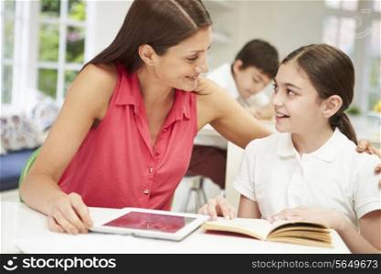 Mother Helping Daughter With Homework Using Digital Tablet