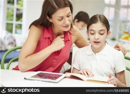 Mother Helping Daughter With Homework Using Digital Tablet