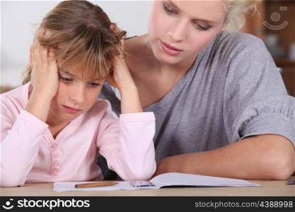 Mother helping her daughter with her homework.