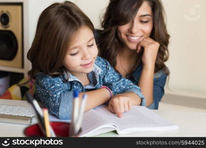 Mother helping her little child with homework