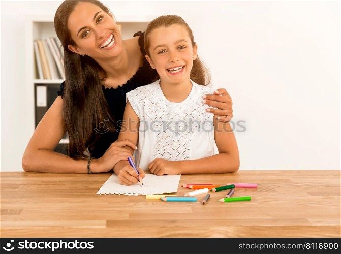 Mother helping her little daughter making drawings