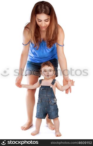 Mother helping her little son doing his first steps, holding hands and walking in the studio, isolated on white background