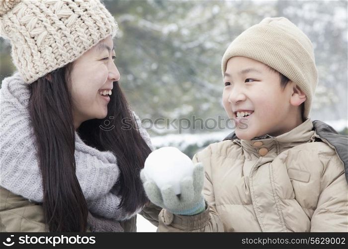 Mother helping son make snow ball