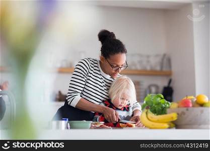 Mother helping son prepare food in kitchen