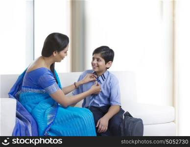 Mother helping son with neck tie
