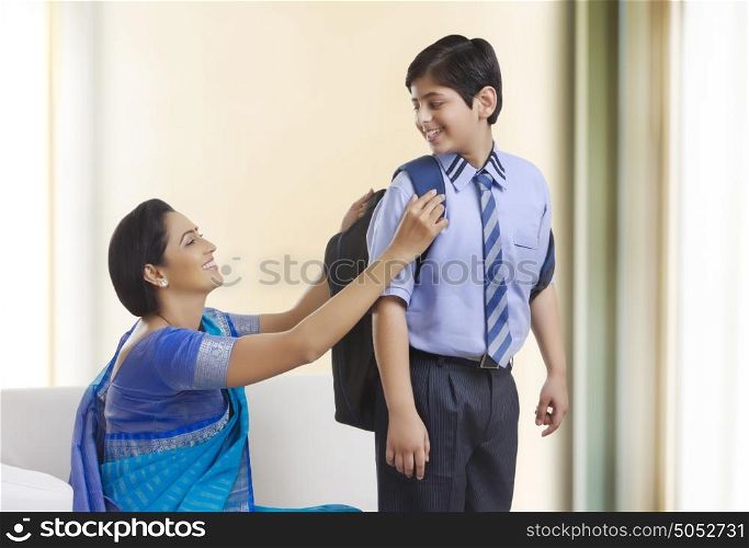 Mother helping son with school bag