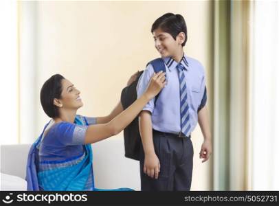 Mother helping son with school bag