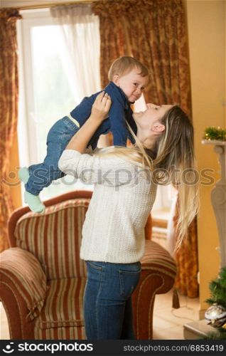 Mother holding 10 months old baby son and decorating Christmas tree