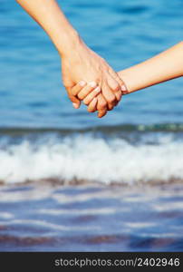 Mother holding a hand of his son in summer day outdoors