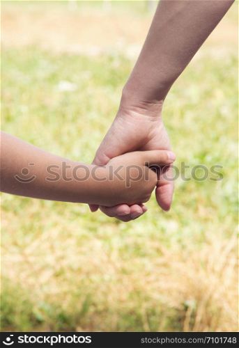 Mother holding a hand of his son in summer day outdoors