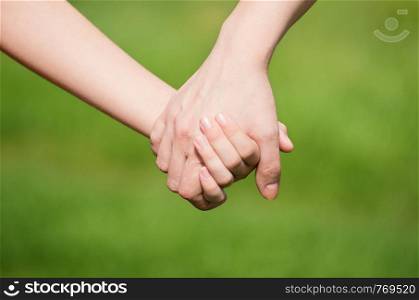 Mother holding a hand of his son in summer day outdoors