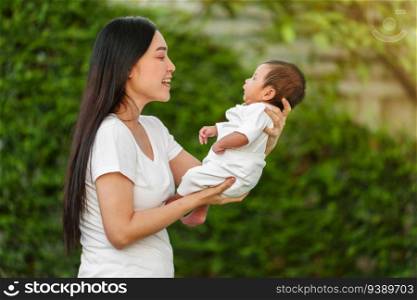 mother holding and playing with her baby newborn in the garden