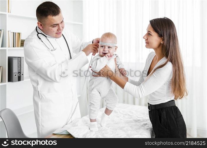 mother holding baby while doctor looking it