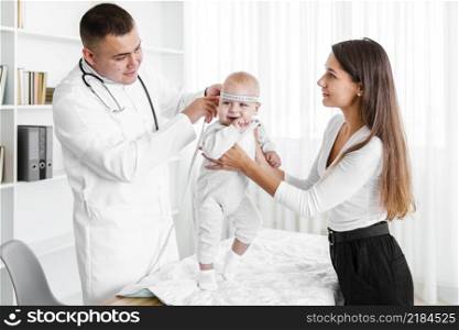 mother holding baby while doctor looking it