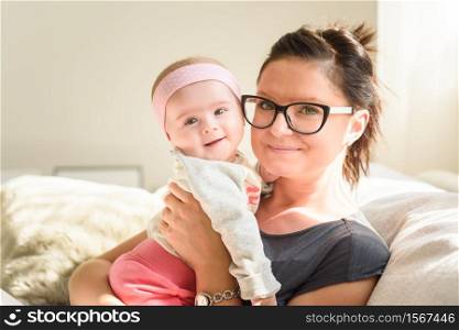Mother holding beautiful baby girl in bright sunny room. Motherhood background. Mother holding beautiful happy baby girl in bright sunny room. Motherhood concept