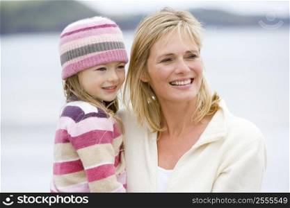 Mother holding daughter at beach smiling