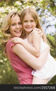 Mother holding daughter outdoors smiling
