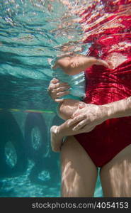 Mother holding daughter underwater in swimming pool