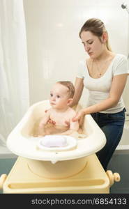 Mother holding her baby in towel at bathroom
