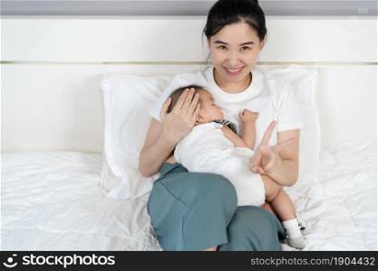 mother holding newborn baby sleeping in her arm on a bed