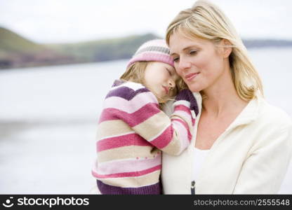 Mother holding sleeping daughter at beach