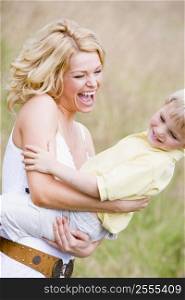 Mother holding son outdoors smiling