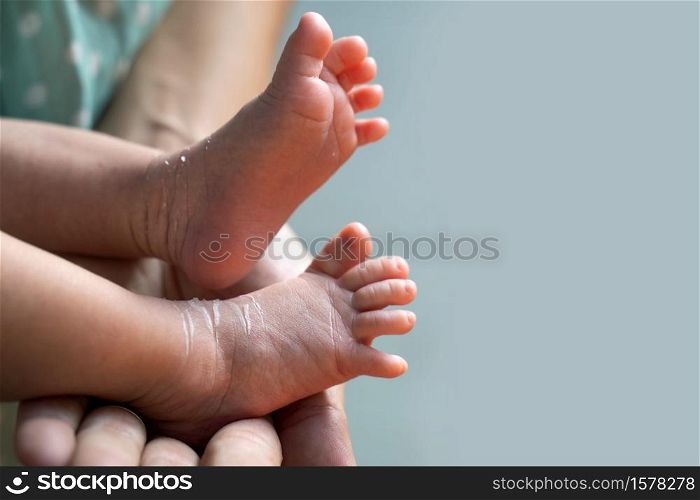 Mother holding tiny foot of newborn baby skin. Mother holding foot of baby